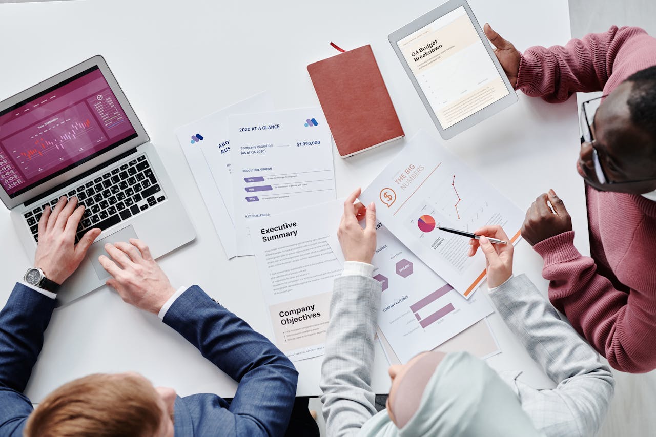 services-02 Top view of a diverse team collaborating on digital devices and papers in an office setting.