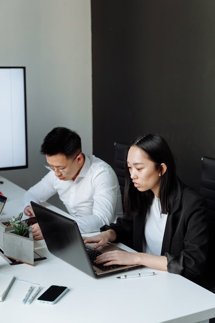 services-04 Two professionals focusing on their tasks in an office environment, using laptops.